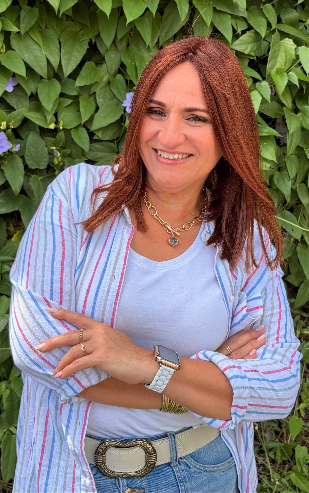 Mila Baerga Portrait, Woman with red hair standing in front of green foliage 